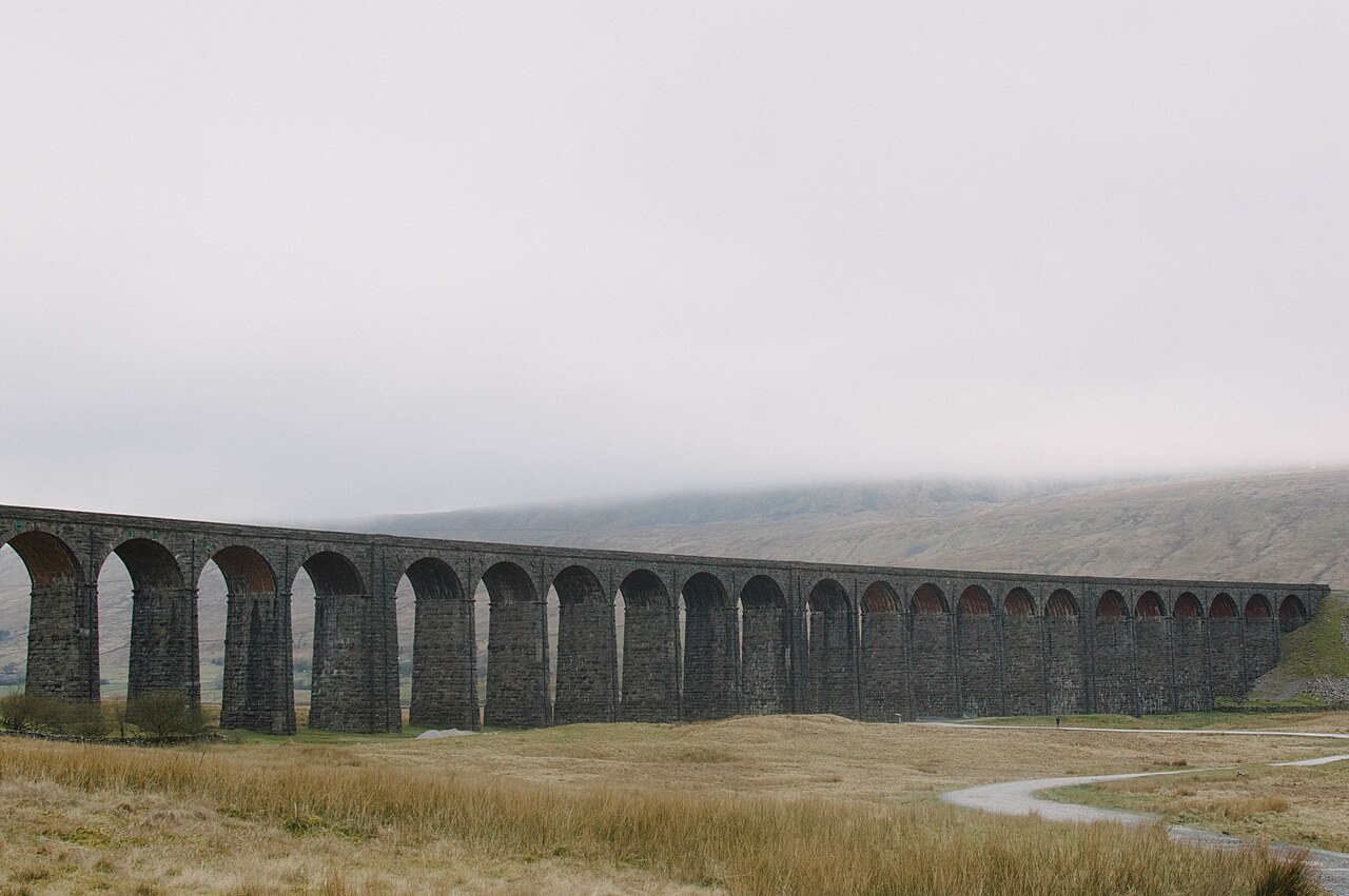 The arches of Ribblehead Viaduct crossing open countryside in the Yorkshire Dales.
