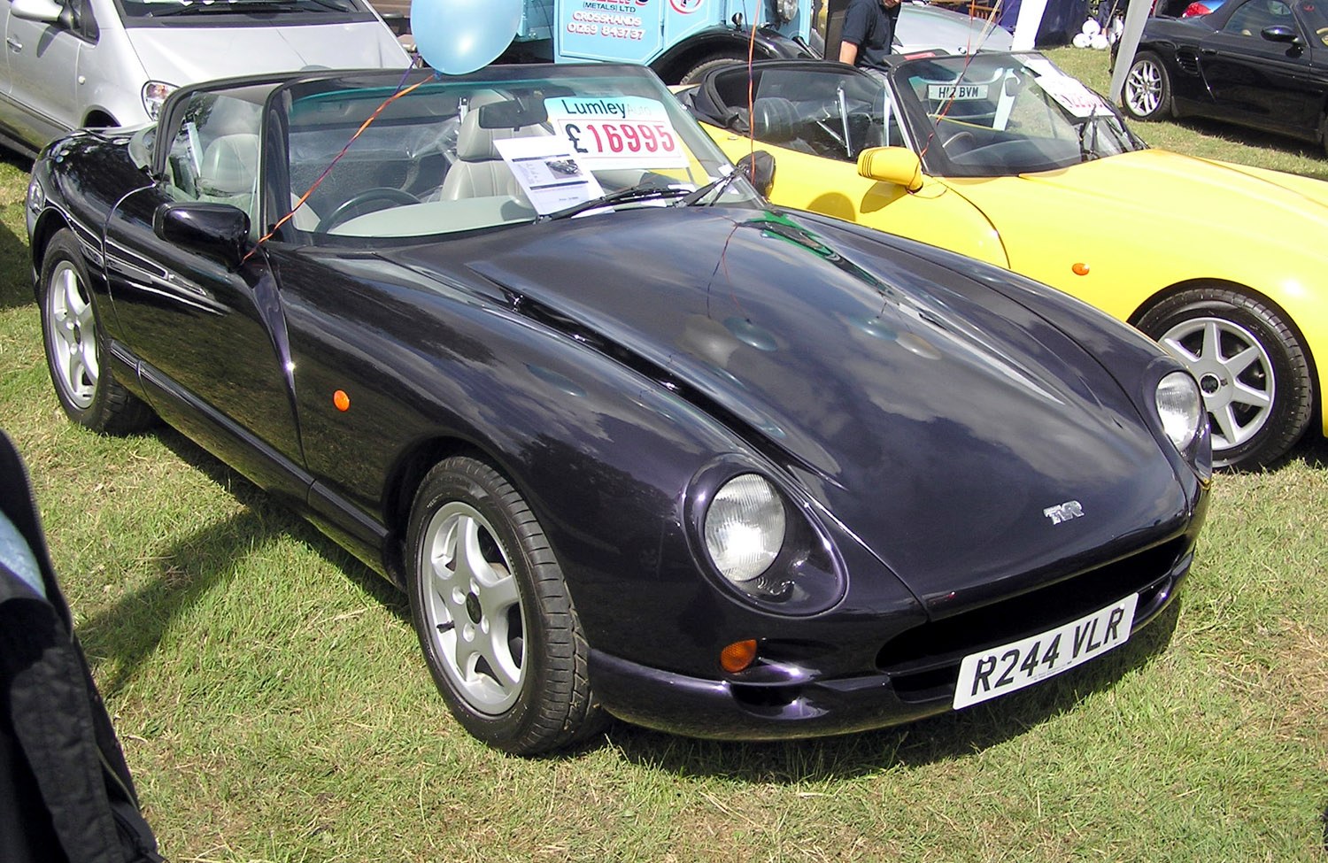 A black TVR Chimaera with its roof down at an outdoor car show.